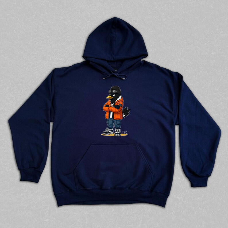 Puede incluir: Sudadera con capucha azul marino con un personaje de dibujos animados de un p&aacute;jaro que lleva gafas de sol, una chaqueta naranja y vaqueros. El p&aacute;jaro tiene los brazos cruzados. La sudadera tiene un bolsillo delantero y una capucha con cord&oacute;n.