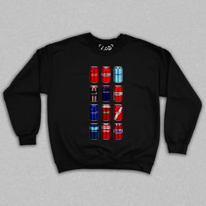 Könnte beinhalten: Schwarzes Sweatshirt mit einem Raster aus zwölf bunten Getränkedosen-Designs. Die Dosen haben verschiedene Teamlogos und Designs, darunter rot, blau und weiß. Auf der oberen rechten Ecke des Sweatshirts steht der Text "/.OD".