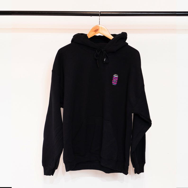 May include: Black hooded sweatshirt with a small embroidered design of a pink and blue striped can on the front.