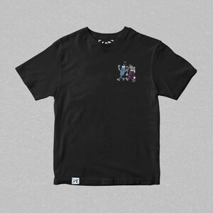 May include: Black t-shirt with a small, colorful graphic of two cartoon figures. One figure is blue and the other is purple. The shirt has a crew neck and short sleeves. The brand logo is visible at the top and bottom of the shirt.