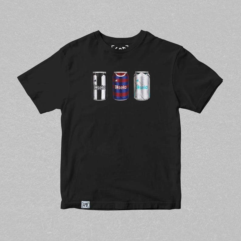 K&ouml;nnte beinhalten: Schwarzes T-Shirt mit einem Aufdruck von drei Aluminiumdosen. Jede Dose zeigt das Trikotdesign eines anderen Fu&szlig;ballteams. Der Text "Basela" ist auf jeder Dose aufgedruckt.