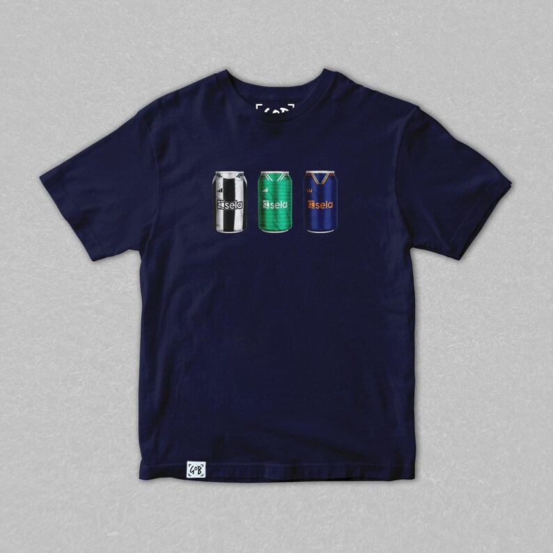 May include: Navy blue t-shirt featuring three stylized beverage cans. The cans are decorated with team colors and logos. The text "fasela" is printed on each can. The shirt has a crew neck and short sleeves.