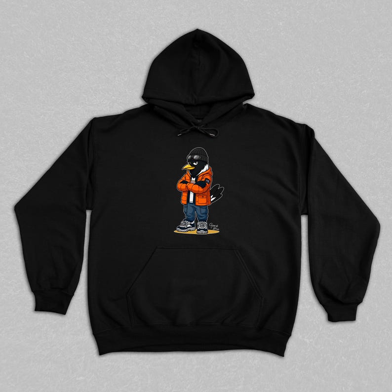 Puede incluir: Sudadera con capucha negra con un personaje de cuervo de dibujos animados que lleva gafas de sol, una gorra negra, una chaqueta naranja, vaqueros azules y zapatillas deportivas. El cuervo tiene los brazos cruzados. La sudadera tiene un bolsillo delantero.