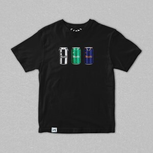 May include: Black t-shirt featuring three stylized beverage can designs. The cans are in the colors of soccer jerseys: black and white stripes, green, and blue with a yellow V-neck design. The word "fasela" is printed on each can.