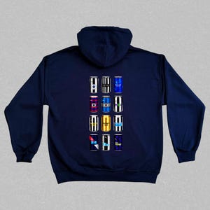 May include: A navy blue hoodie with a design of 12 different colored cans on the back. Each can has a different design and color scheme.