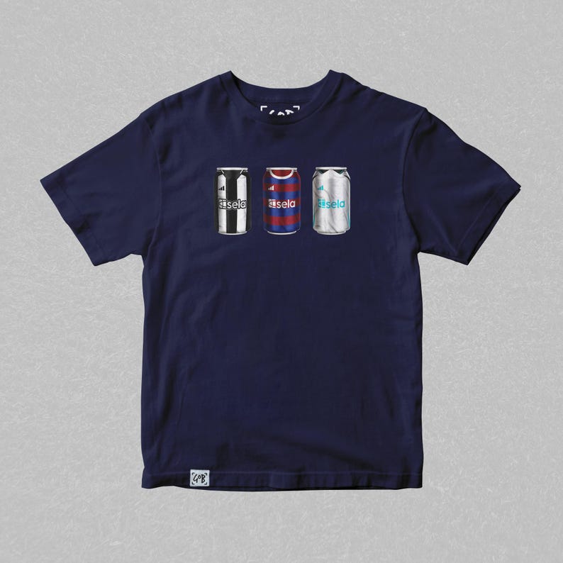 K&ouml;nnte beinhalten: Ein marineblaues T-Shirt mit einem Aufdruck von drei Aluminiumdosen. Jede Dose ist mit dem Trikot eines anderen Fu&szlig;ballteams gestaltet. Die Dosen sind mit "Basela" beschriftet.