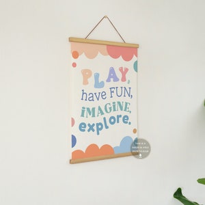 May include: A printable wall art print with a white background and colorful text that reads "PLAY, have FUN, IMAGINE, explore." The text is surrounded by colorful circles and clouds.