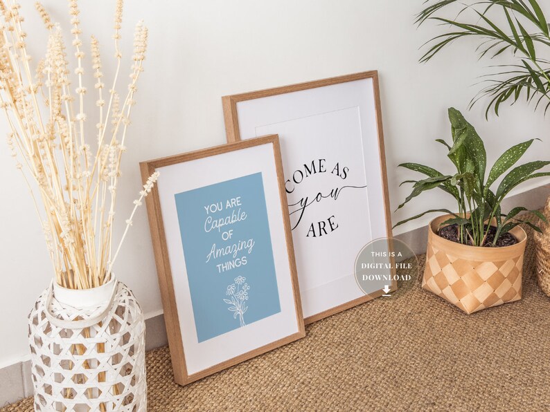 May include: Two framed prints with inspirational quotes. The print on the left says "You are capable of amazing things" in white text on a light blue background. The print on the right says "Come as you are" in black cursive text on a white background.