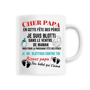 Peut inclure: Mug en céramique blanche avec un motif noir et bleu. Le mug présente le texte "Cher Papa" et "Bisous papa!" ainsi qu'une bouteille de lait, un bébé dans un ventre et deux empreintes de pieds de bébé.