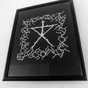 Puede incluir: Una imagen enmarcada en negro con un diseño en forma de cruz blanca en el centro. El diseño está rodeado por un borde de líneas blancas.