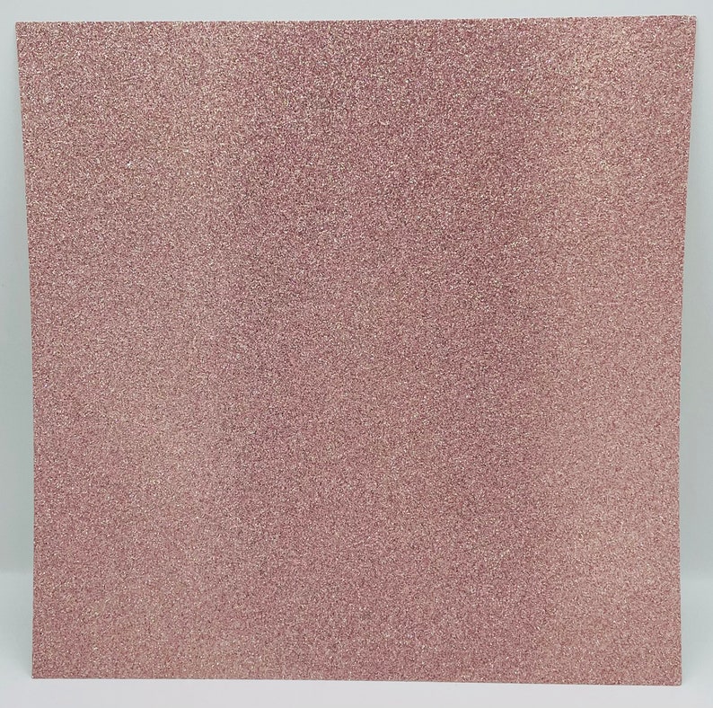 May include: A sheet of rose gold glitter paper. The paper has a fine, even glitter texture.