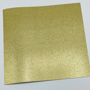 May include: A sheet of gold glitter paper. The paper has a fine, even glitter texture.