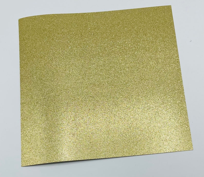 May include: A sheet of gold glitter paper. The paper has a fine, even glitter texture.