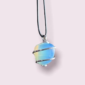 May include: A blue opal gemstone wrapped in silver wire, hanging from a black cord necklace.