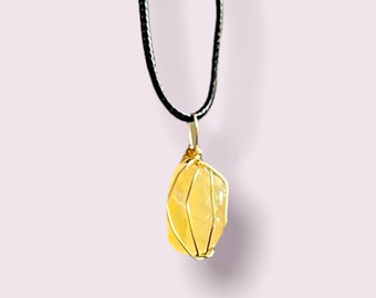 Puede incluir: Un colgante de cristal amarillo envuelto en alambre dorado, colgando de un collar de cordón negro.