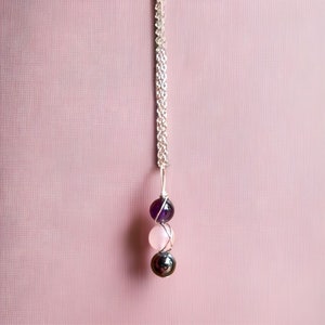May include: A silver chain necklace with a pendant featuring three round gemstones: amethyst, rose quartz, and hematite.