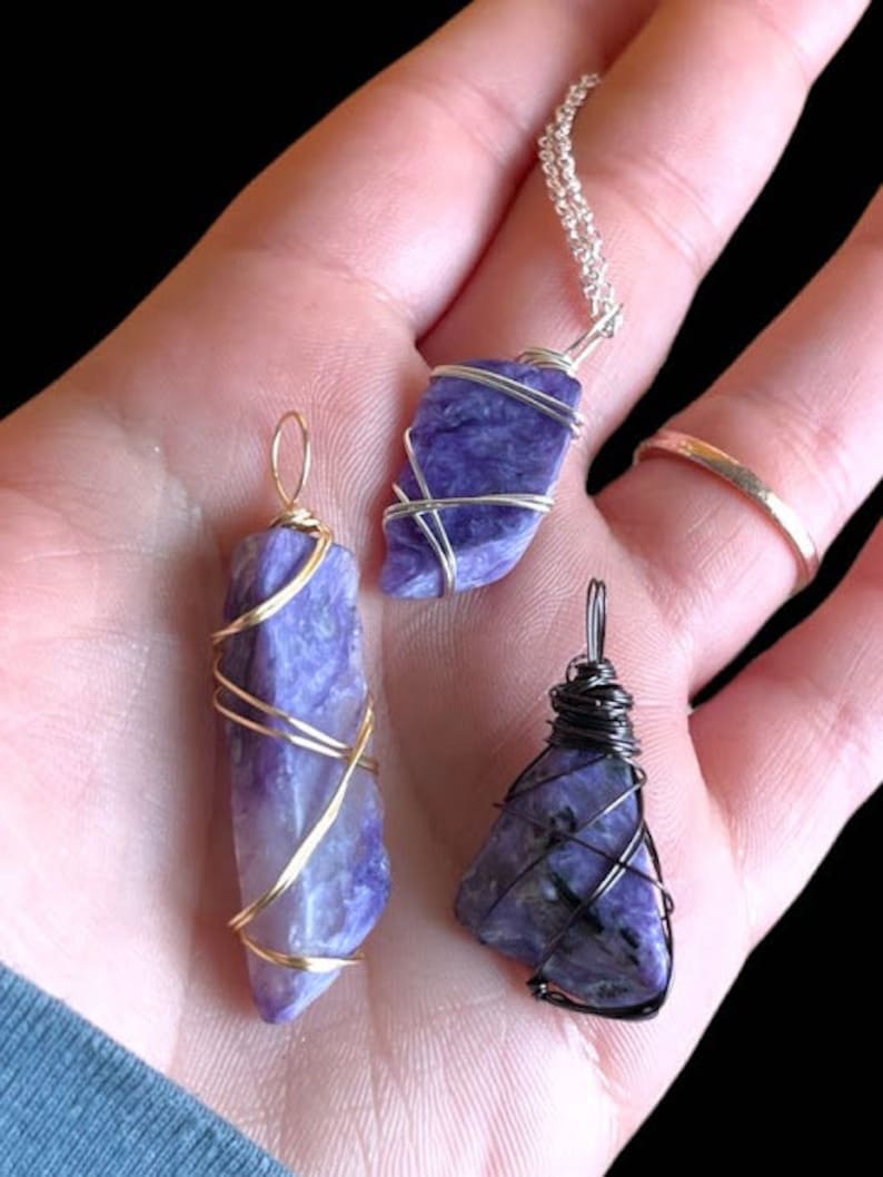 May include: Three wire-wrapped pendants featuring purple and blue stones. The pendants are made with gold and silver wire. The stones are wrapped in a variety of patterns.
