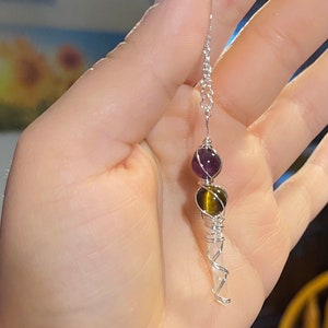 Könnte beinhalten: Eine silberne Kettenkette mit einem klaren Quarzkristall, einer Tigeraugenperle und einer Amethystperle.