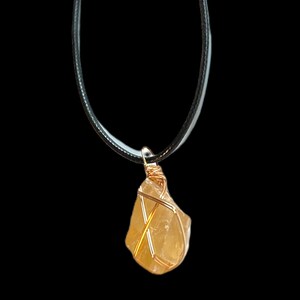 May include: A gold wire wrapped yellow citrine crystal pendant on a black cord necklace.