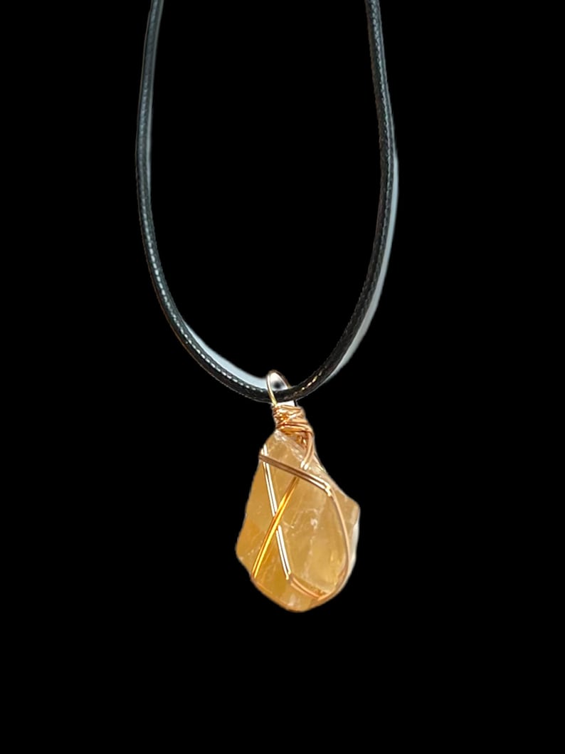 May include: A gold wire wrapped yellow citrine crystal pendant on a black cord necklace.