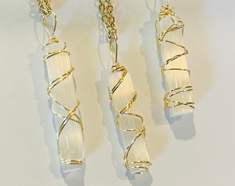 May include: Three gold wire wrapped selenite crystal pendants on gold chains. The selenite crystals are white and translucent.