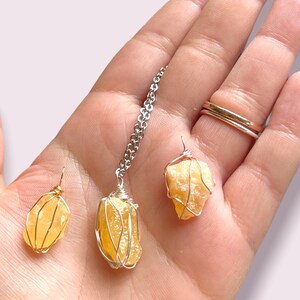 May include: Three yellow citrine crystal pendants wrapped in wire, one on a silver chain. The pendants are different sizes and shapes.