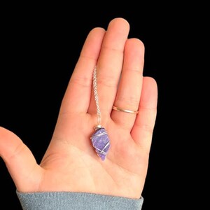 May include: A silver chain necklace with a purple amethyst crystal pendant wrapped in silver wire.