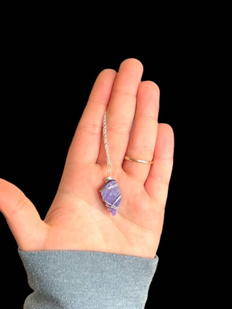 May include: A silver chain necklace with a purple amethyst crystal pendant wrapped in silver wire.