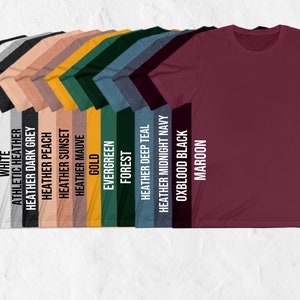 May include: A selection of t-shirts in various colors, including black, white, heather grey, heather peach, heather sunset, heather mauve, gold, evergreen, forest, heather deep teal, heather midnight navy, oxblood black, and maroon.