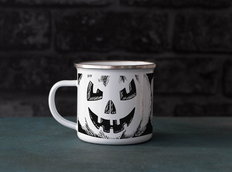 May include: White enamel mug with a black and white illustration of a jack-o'-lantern face.