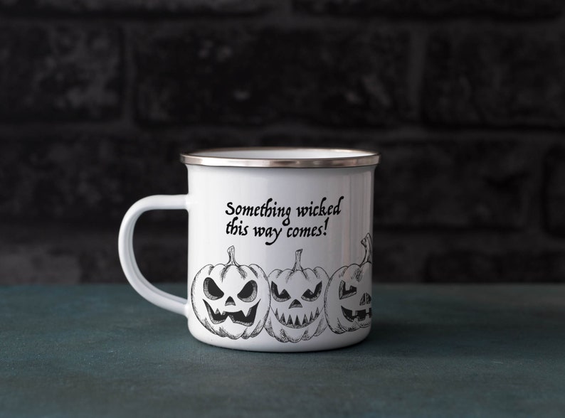 May include: White enamel camping mug with a black and white illustration of jack-o'-lanterns and the text "Something wicked this way comes!"