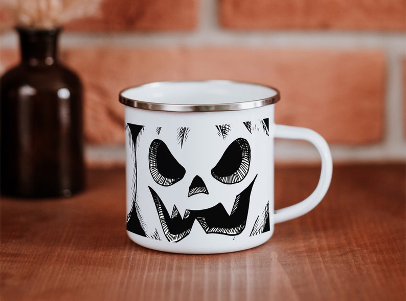 May include: White enamel mug with a black and white illustration of a jack-o'-lantern face.