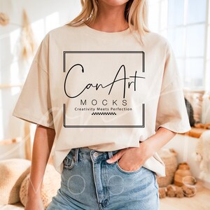 Op de afbeelding: Een beige oversized t-shirt met een zwart vierkant frame rond de tekst "CanArt MOCKS Creativity Meets Perfection".
