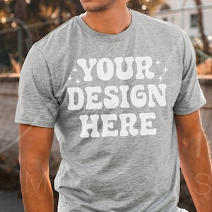 May include: A heather grey t-shirt with the text "YOUR DESIGN HERE" in white. The text is in a retro font style with stars on either side.