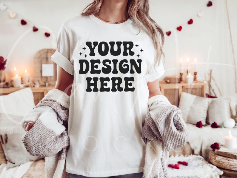 May include: A white t-shirt with the text "YOUR DESIGN HERE" in black lettering. The shirt is being worn by a person in a casual setting.