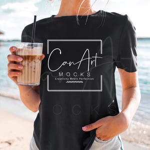May include: A black t-shirt with a white graphic that says "Can Art Mocks" and "Creativity Meets Perfection". The shirt is being worn by a person on a beach.