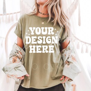 May include: A green t-shirt with the text "YOUR DESIGN HERE" in white. The shirt is being modeled by a person with long blonde hair.