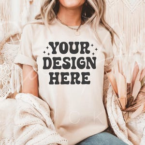 May include: A beige t-shirt with the text "YOUR DESIGN HERE" in black retro-style lettering.