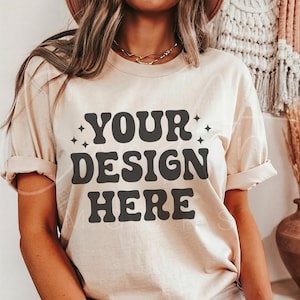 May include: A beige t-shirt with the text "YOUR DESIGN HERE" in black retro-style lettering.