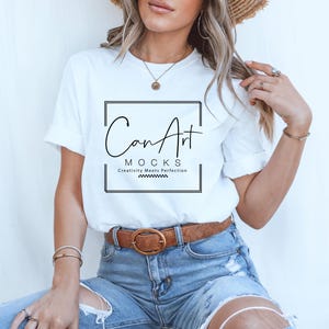 Pode incluir: Uma camiseta branca com um gr&aacute;fico preto que diz "CanArt" e "MOCKS Creativity Meets Perfection". A camiseta est&aacute; sendo usada por uma pessoa com cabelo longo e loiro e um chap&eacute;u de palha. A pessoa est&aacute; usando jeans azul com um cinto marrom.
