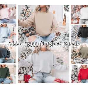 Könnte beinhalten: Ein Bündel aus zehn Gildan 18000 Rundhals-Sweatshirts in verschiedenen Farben, darunter rosa, beige, hellblau, schwarz, grün, grau und rot. Die Sweatshirts werden vor einem Hintergrund aus Weihnachtsdekorationen gezeigt.