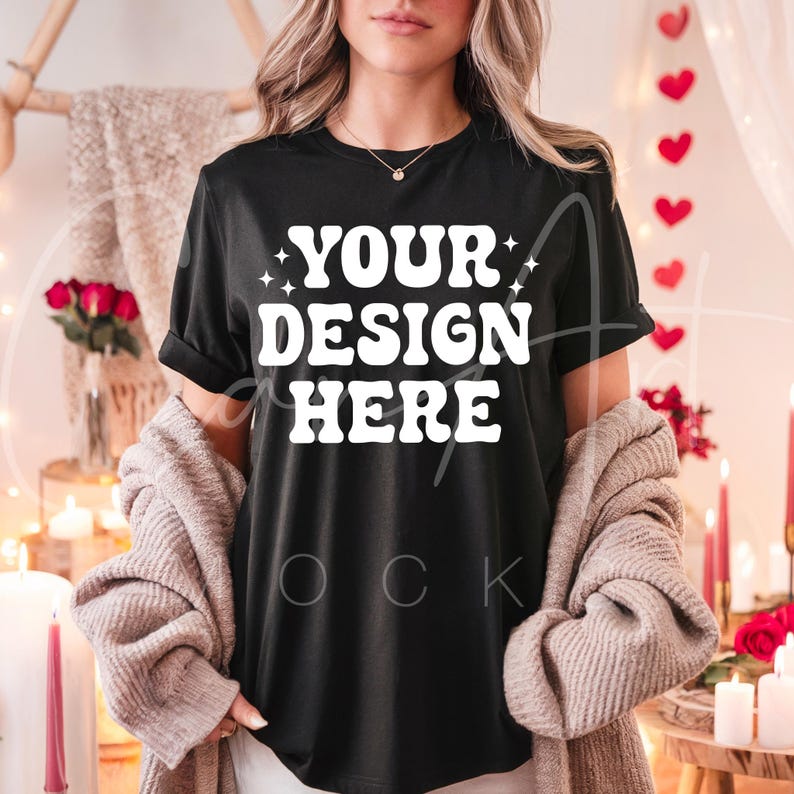 May include: A black t-shirt with the text "YOUR DESIGN HERE" in white. The shirt is being modeled by a person wearing a white cardigan.