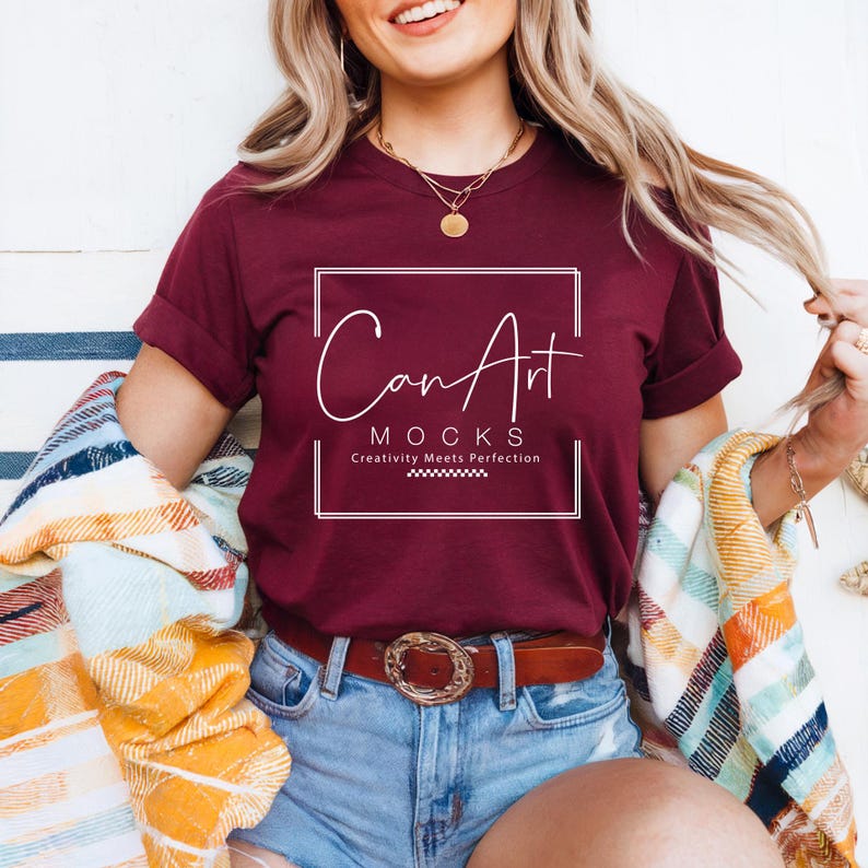Pode incluir: Uma camiseta vinho com um gr&aacute;fico quadrado branco que diz "Can Art Mocks" e "Creativity Meets Perfection".