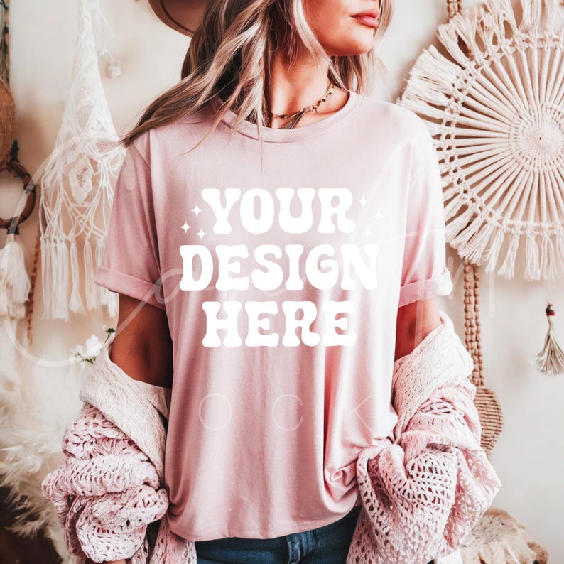 May include: A pink t-shirt with the text "YOUR DESIGN HERE" in white. The shirt is being worn by a person with long blonde hair and a cardigan.