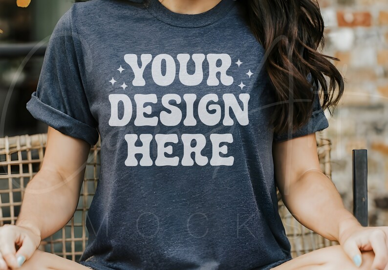 Puede incluir: Una camiseta azul oscuro con el texto "YOUR DESIGN HERE" en blanco, con un estilo de fuente retro.