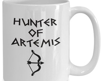 May include: White ceramic mug with black text that reads "HUNTER OF ARTEMIS" and a black and white illustration of a bow and arrow.