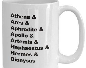 May include: White ceramic coffee mug with black text listing the names of Greek gods and goddesses: Athena, Ares, Aphrodite, Apollo, Artemis, Hephaestus, Hermes, and Dionysus.