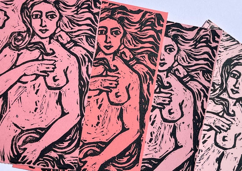 May include: A collection of pink and black linocut prints. Each print features a nude female figure with long flowing hair, her hand gently touching her chest. The prints are displayed in a fan-like arrangement.