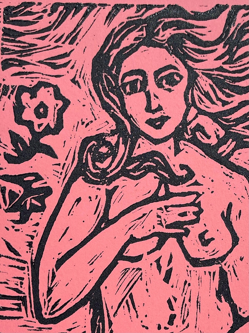 May include: A pink and black linocut print of a woman with long flowing hair. The woman is holding her arms across her chest. A flower and foliage are in the background. The art is a stylized, expressive representation.