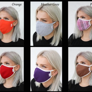 May include: Six different face masks with white trim, shown on six different models with blonde hair. The masks are in the colors orange, heather gray, plaid, red, purple, and brown.